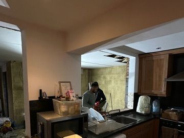 The original kitchen before work: dated wooden units, dark worktop and a damaged ceiling